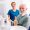 Portrait of satisfied senior male patient sitting at dental chair at dentist office showing thumbs up and smiling with doctor in the background